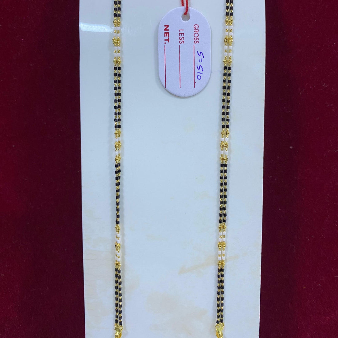 Two gold necklaces on a white card with a red background