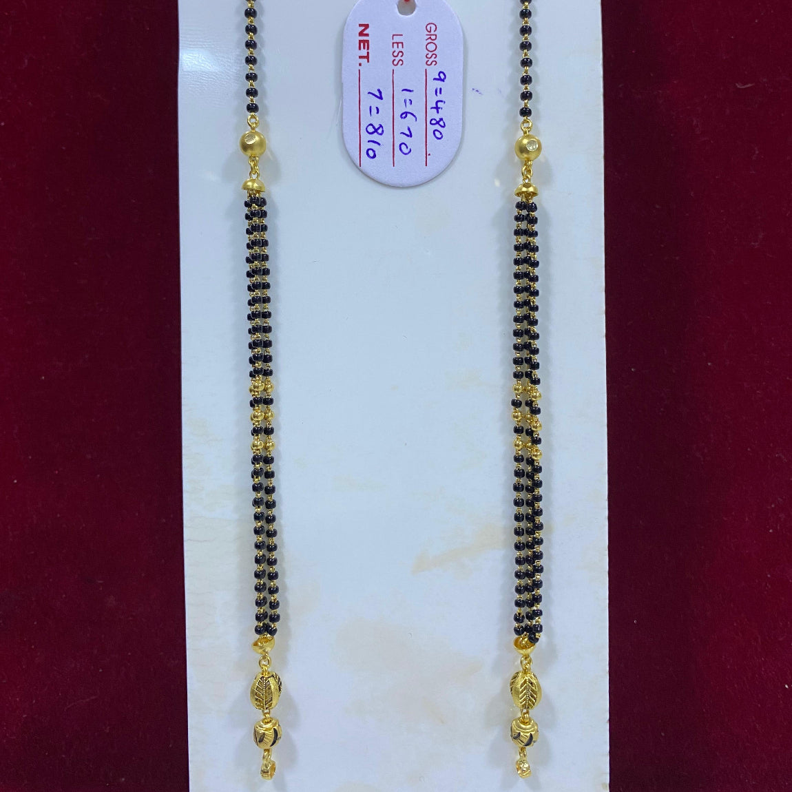 Mangalsutra with gold accents on a white card with a red background
