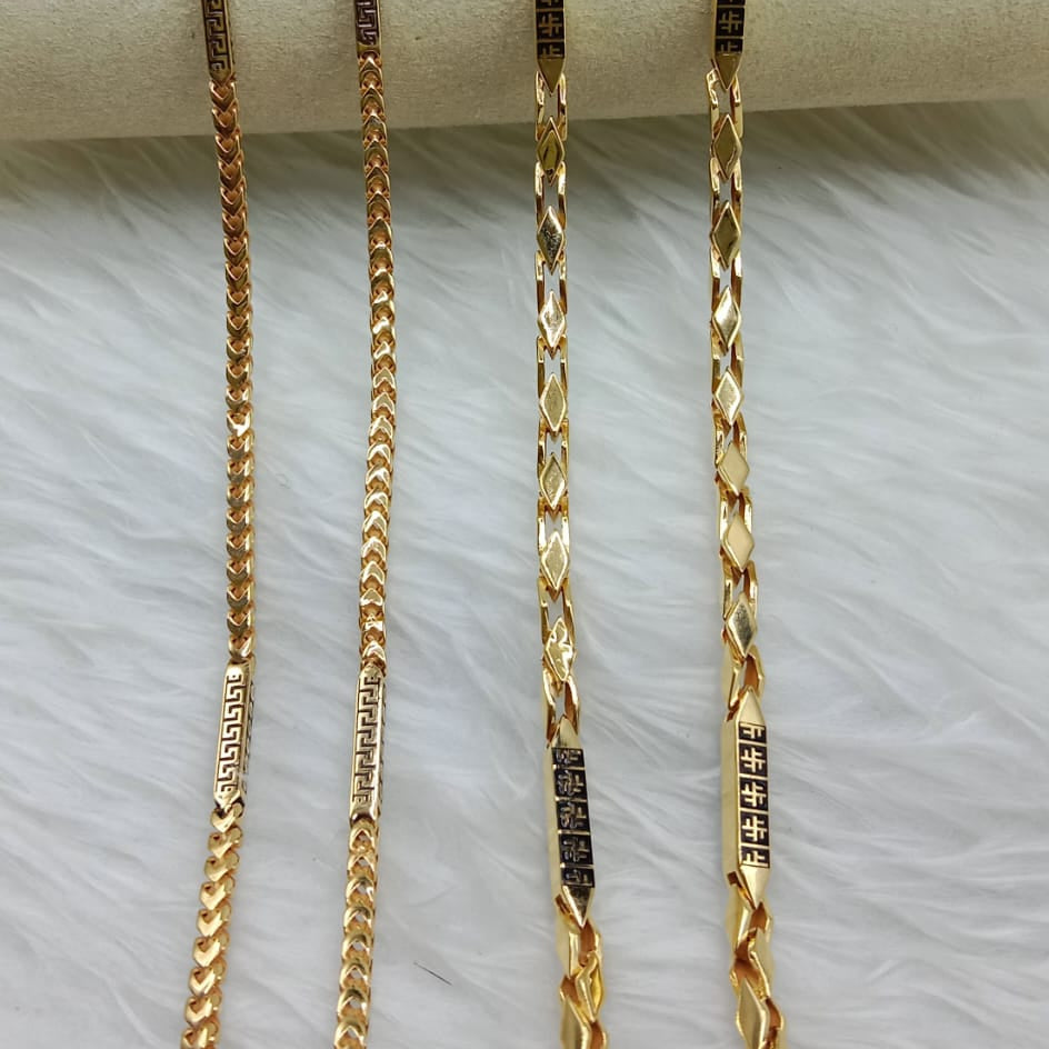 Three gold chains of different lengths on a white surface