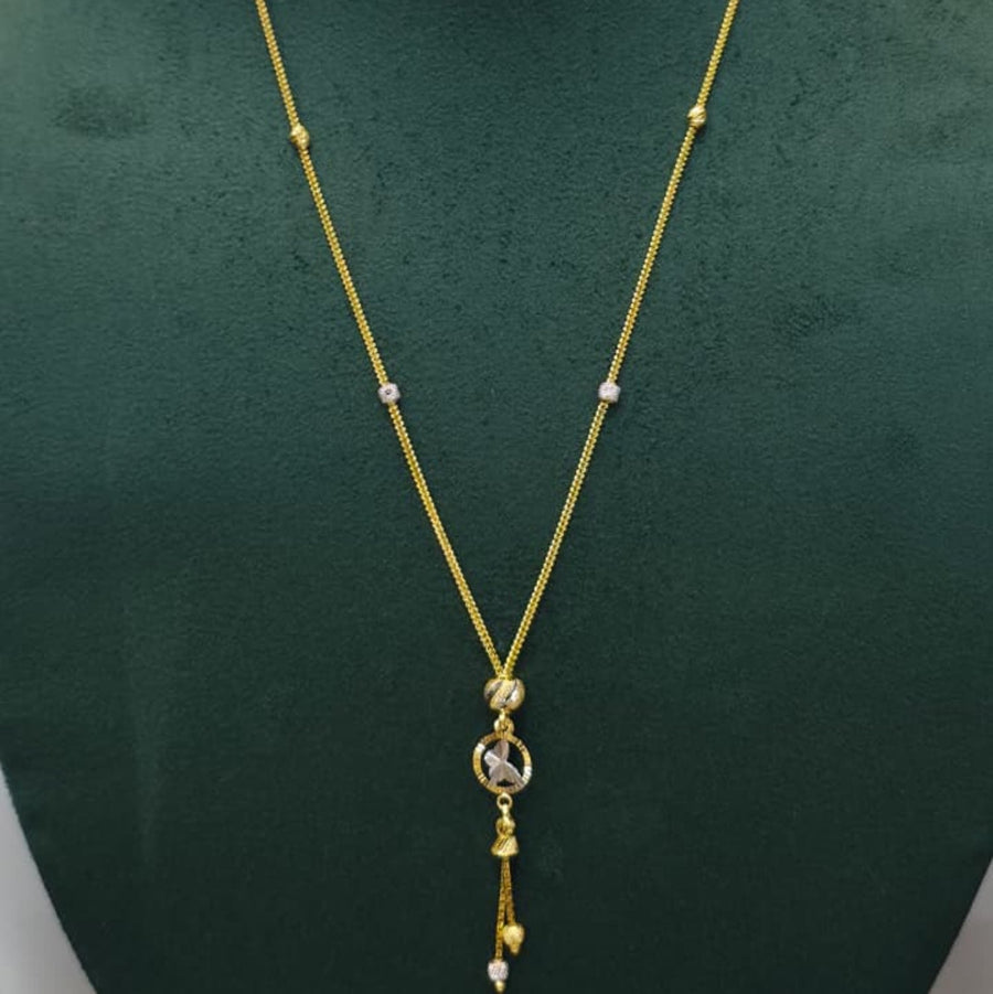 A gold chain necklace with a circular pendant and dangling tassels, displayed on a dark green velvet jewelry bust against a light gray background.
