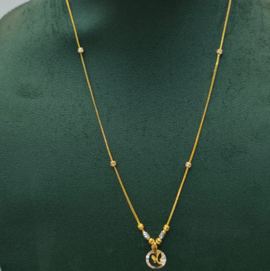 A gold necklace with a small circular pendant displayed on a dark green jewelry bust against a light gray background.