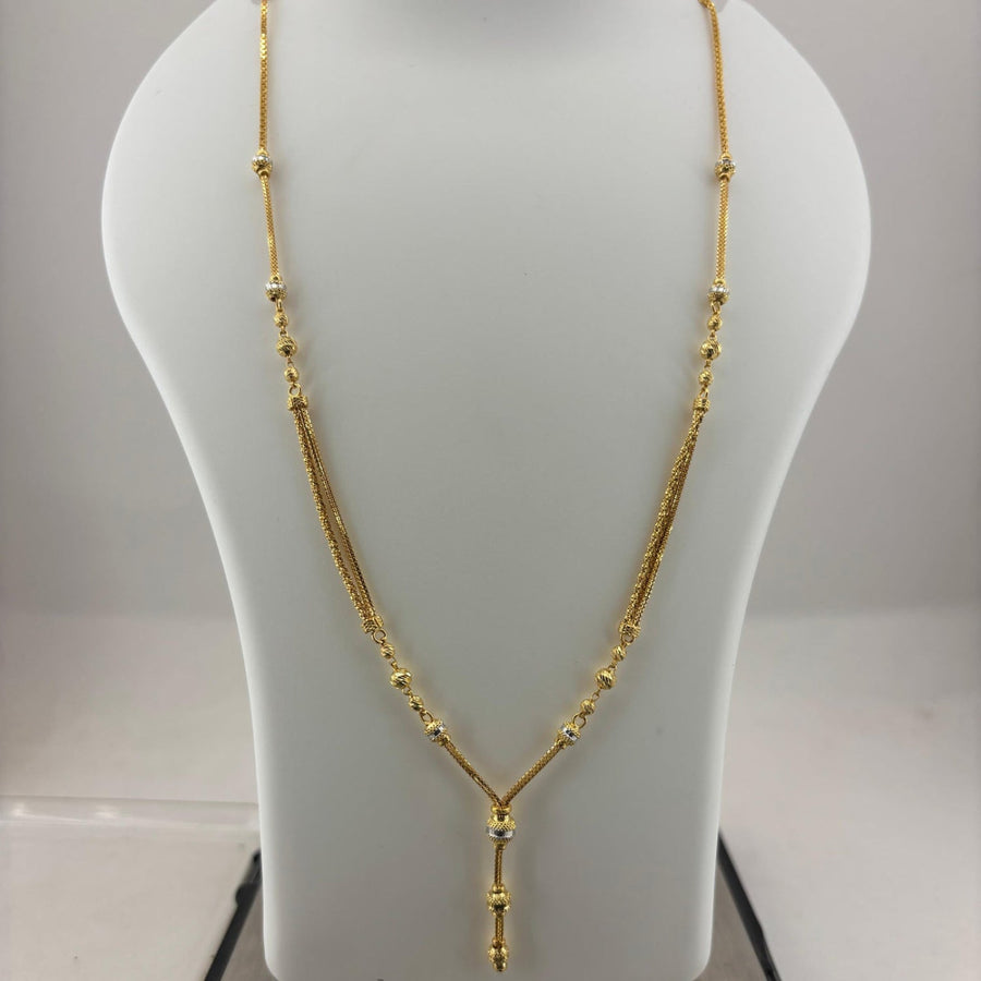 A gold necklace displayed on a white mannequin bust, with a digital scale visible underneath.