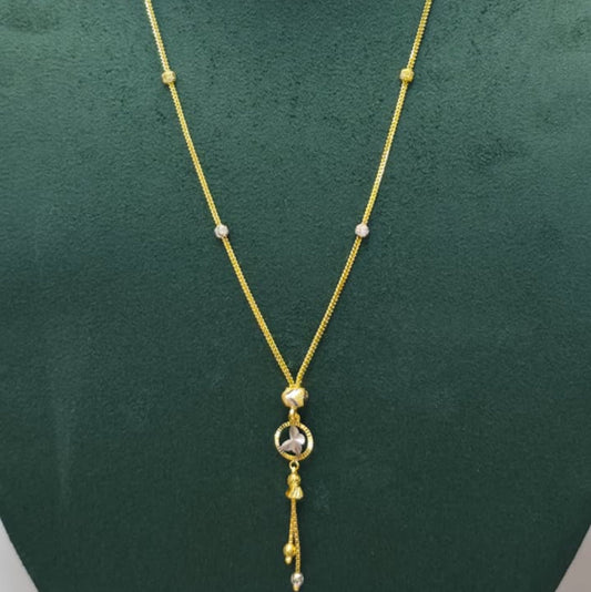 A gold chain necklace with small silver bead accents and a dangling pendant, displayed on a dark green jewelry bust.