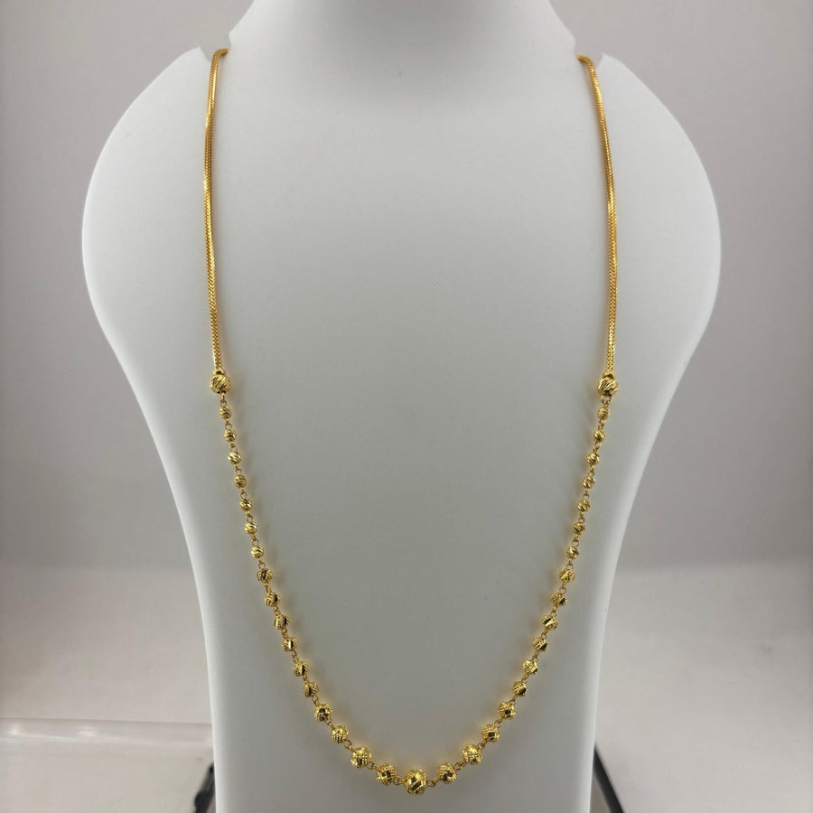 A gold chain necklace displayed on a white mannequin bust, with a digital scale visible underneath.
