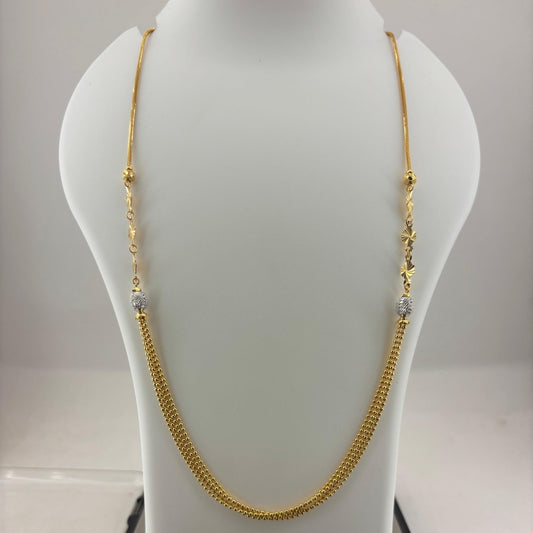 A gold chain necklace with small bead details and clear spacer beads, displayed on a white mannequin bust with a digital scale underneath.
