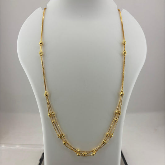 A gold multi-strand beaded necklace displayed on a white mannequin bust, with a digital scale visible underneath.