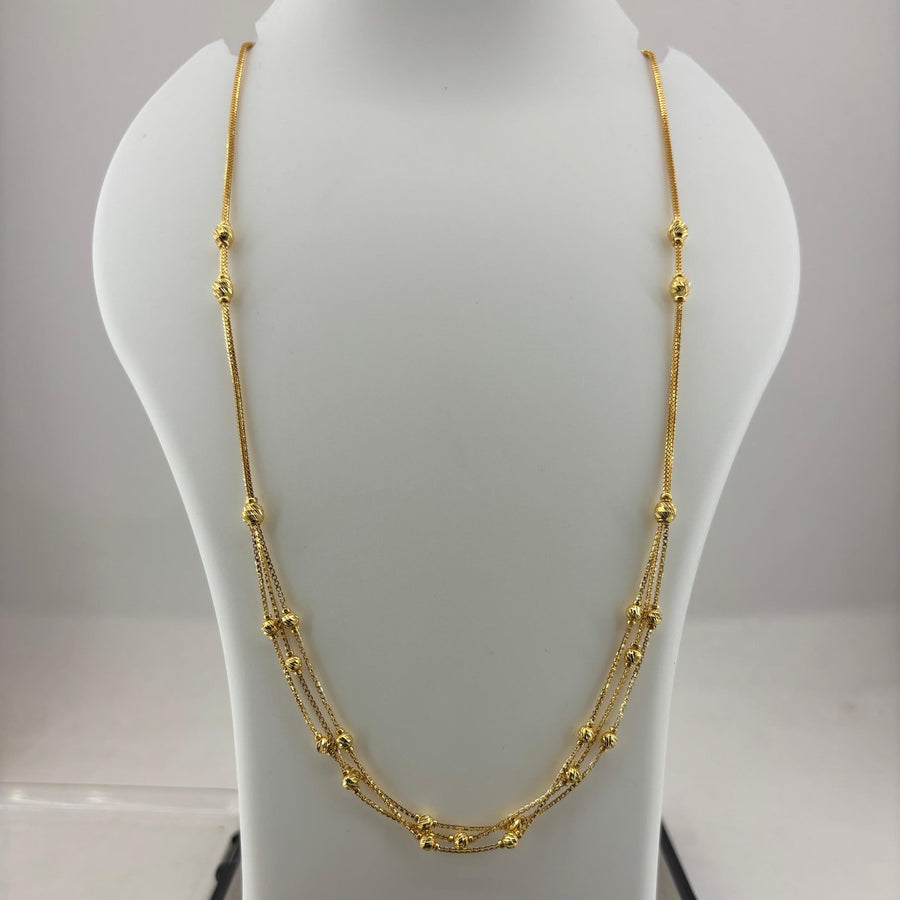 A gold multi-strand beaded necklace displayed on a white mannequin bust, with a digital scale visible underneath.
