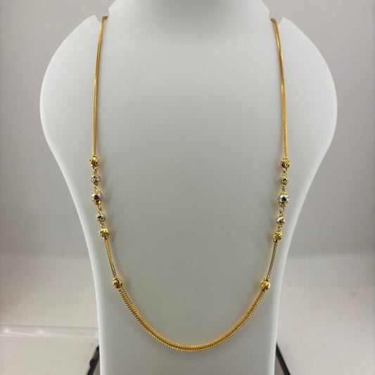 A gold chain necklace with small bead details draped on a white jewelry display bust, with a digital scale visible underneath.
