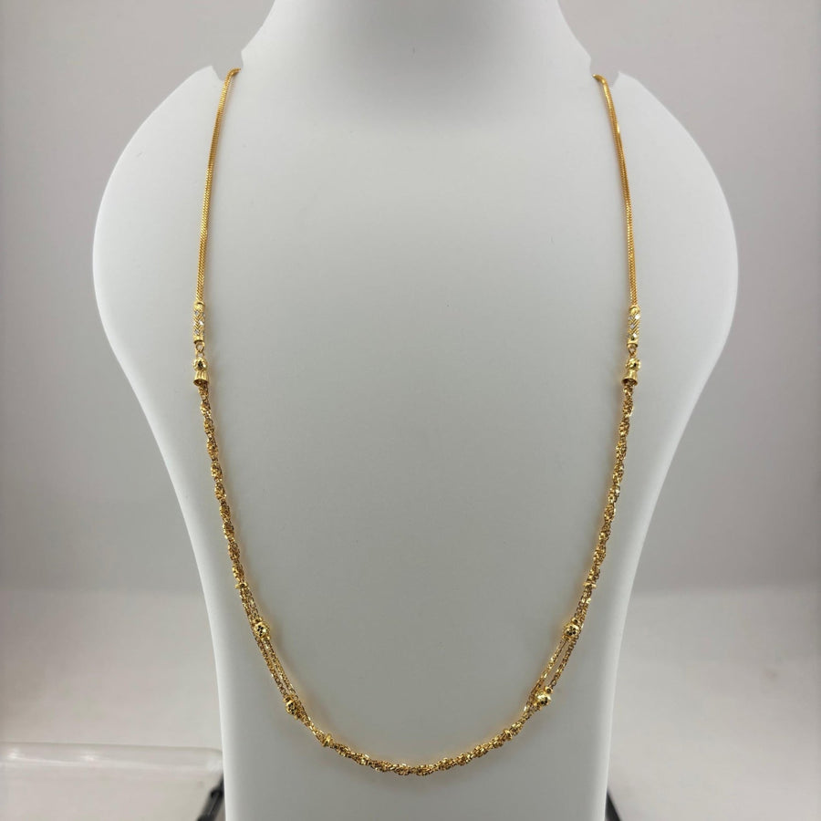 A gold chain necklace displayed on a white mannequin bust, with a digital scale visible underneath. The scale screen shows a weight reading of 8.