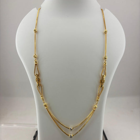 A gold-toned multi-strand necklace with textured bead details, displayed on a white jewelry bust stand with a digital scale underneath.