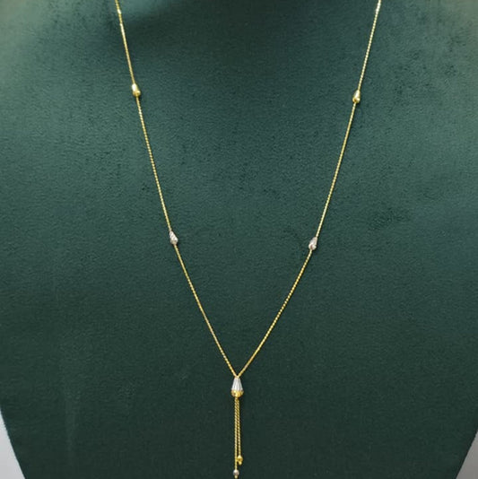 A delicate gold chain necklace with a teardrop-shaped clear stone pendant and small gold bead accents, displayed on a dark green jewelry bust.