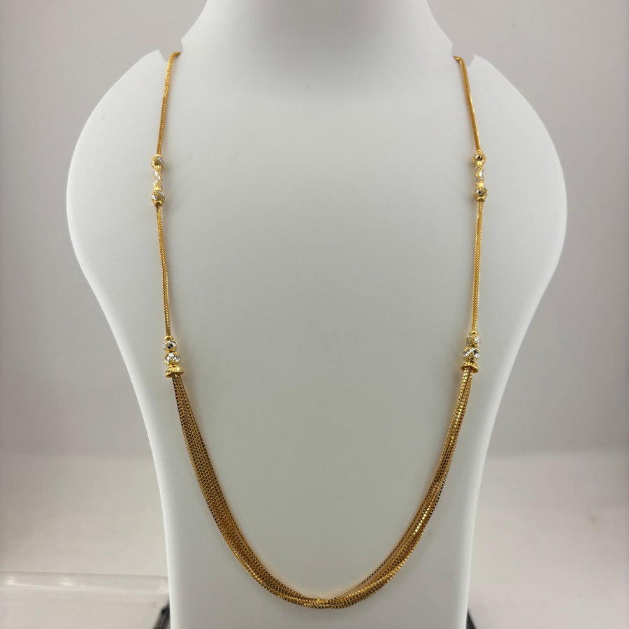 A gold chain necklace displayed on a white mannequin bust, with a digital scale visible underneath.
