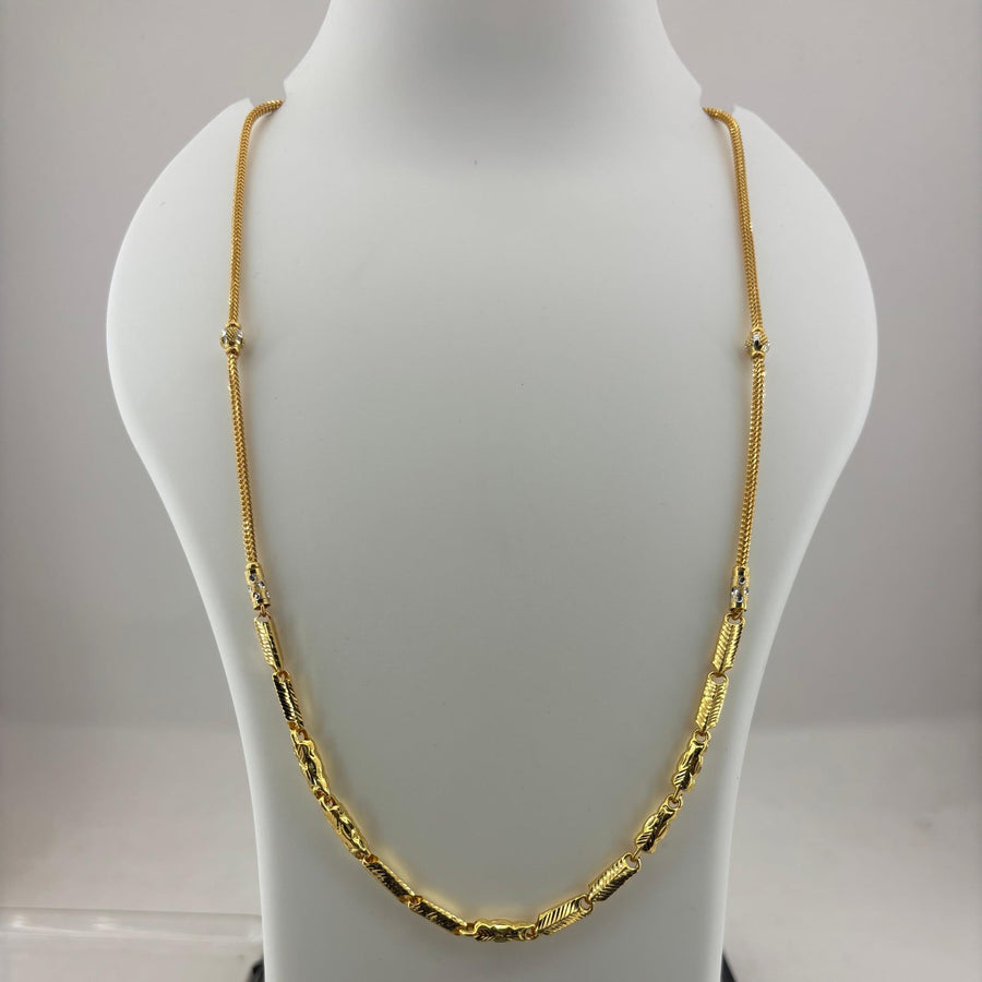 A gold chain necklace displayed on a white jewelry bust, with a digital scale visible underneath.