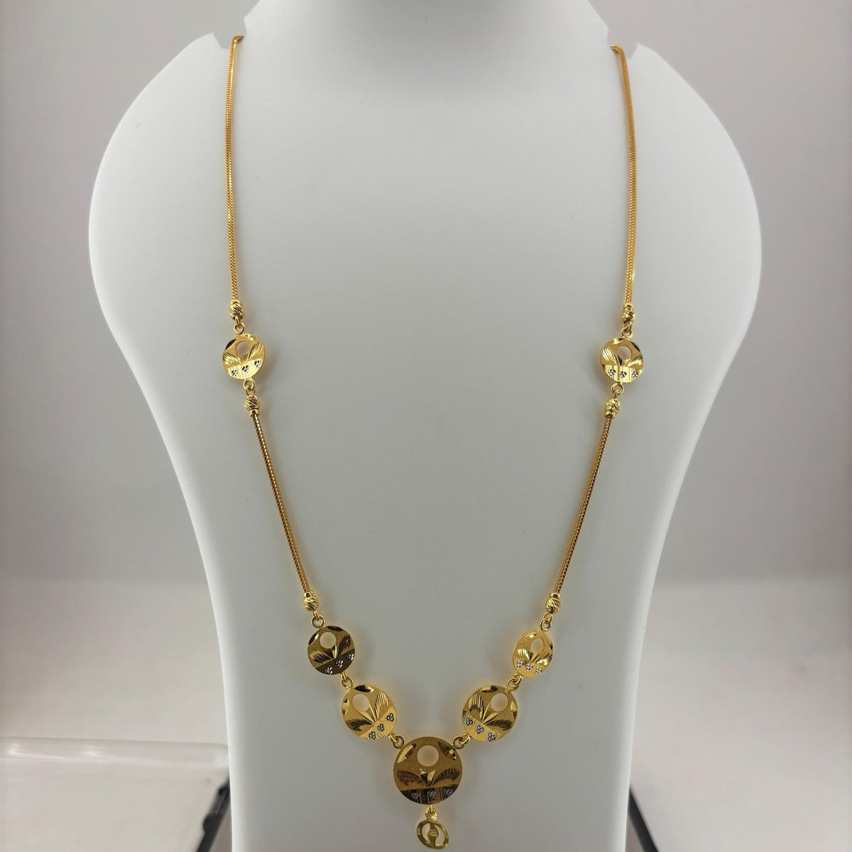 A gold chain necklace with faceted round beads and a central pendant, displayed on a white mannequin bust over a digital scale showing 8.75 grams.