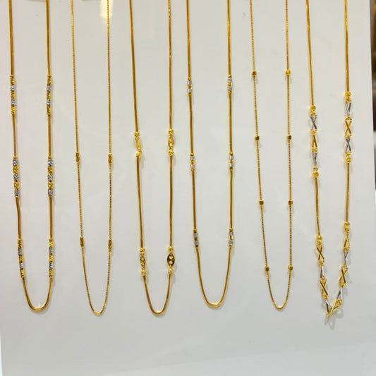 Nine gold chains of varying lengths and styles displayed on a white stand, each with a small price tag attached.