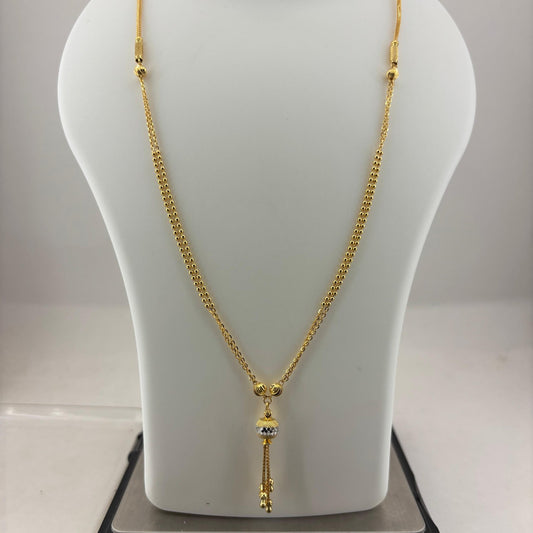 A gold-toned chain necklace with a decorative pendant is displayed on a white mannequin bust, with a digital scale visible underneath.