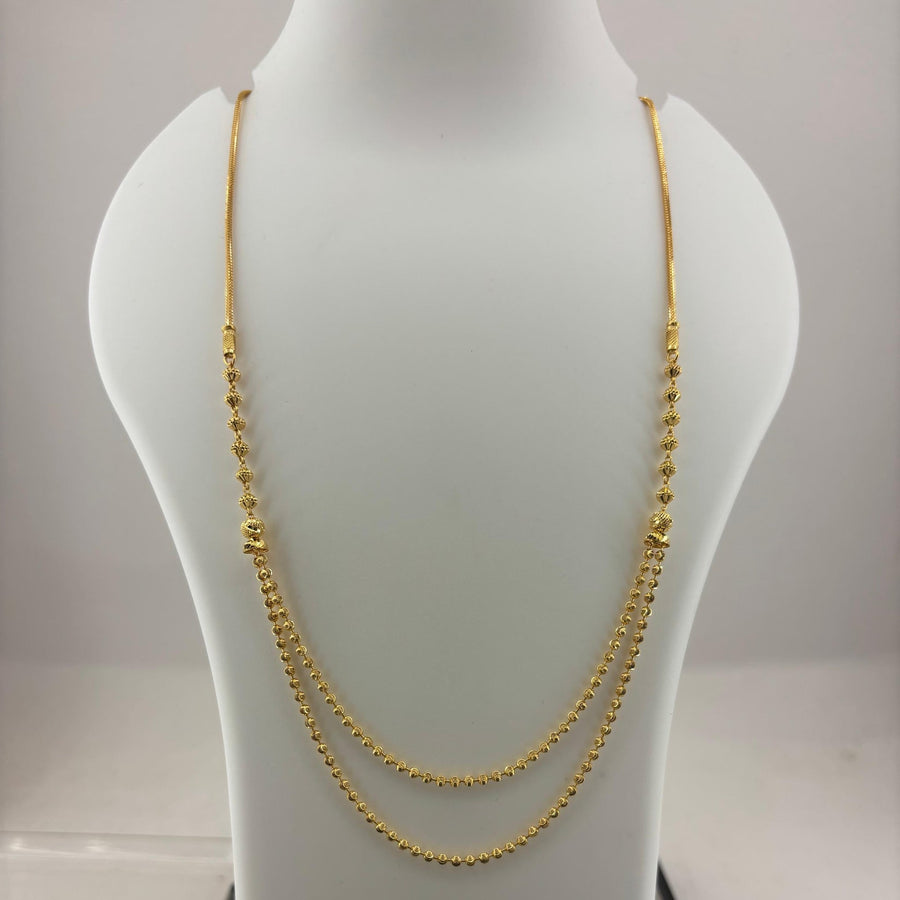 A double-strand gold chain necklace displayed on a white jewelry bust, with a digital scale visible underneath.