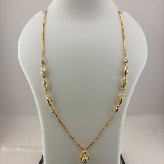 A gold necklace displayed on a white mannequin bust, with a digital scale visible underneath. The necklace features a delicate chain with elongated oval links and a teardrop-shaped pendant at the center.