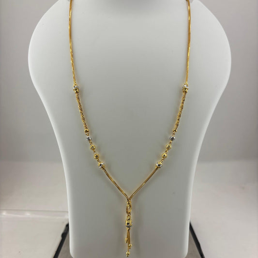 A gold necklace displayed on a white jewelry bust, with a digital scale visible underneath. The necklace has a Y-shaped design with small bead details along the chain.