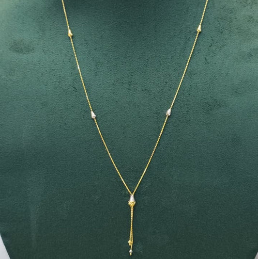 A delicate gold necklace with small bead details and a teardrop-shaped pendant, displayed on a dark green jewelry bust.
