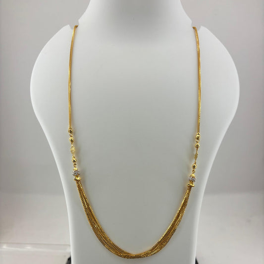 A gold chain necklace displayed on a white mannequin bust, with a digital scale visible underneath. The necklace has a fine chain with small gold bead details and a textured central drop section.