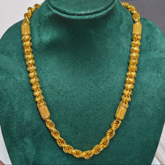 A gold-toned chain necklace displayed on a dark green velvet jewelry bust