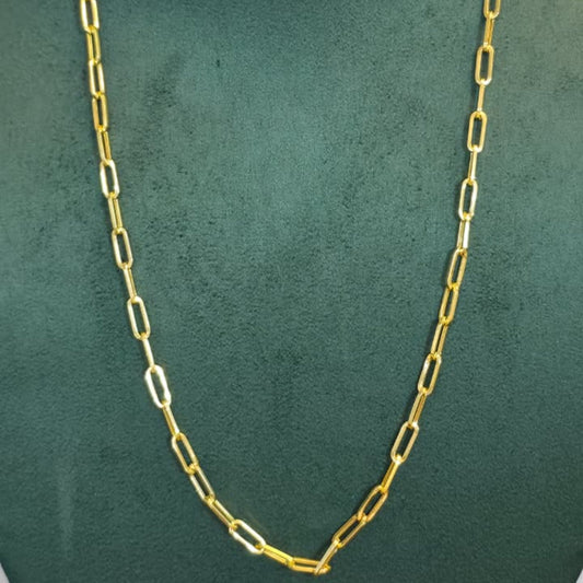 A gold paperclip chain necklace displayed on a dark green velvet jewelry bust against a light gray background.