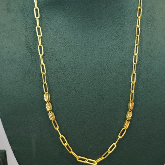 A gold chain necklace with alternating flat oval links and textured cylindrical links, displayed on a dark green velvet jewelry bust.