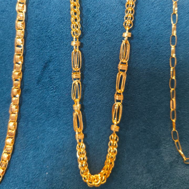 Three gold-toned chain necklaces displayed on a blue velvet jewelry bust against a light pink background.