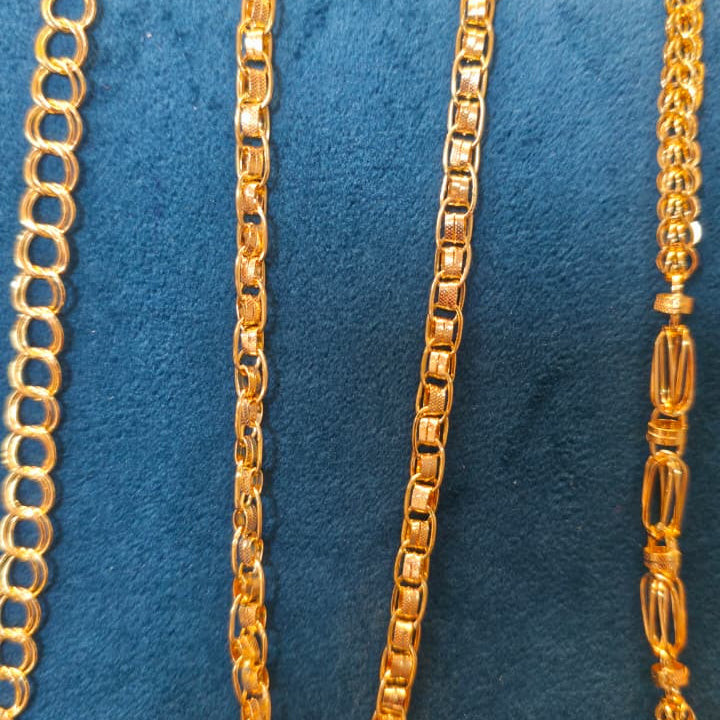 Gold chain necklace displayed on a blue velvet jewelry bust, showing multiple chain styles including curb, box, and Spanish link.