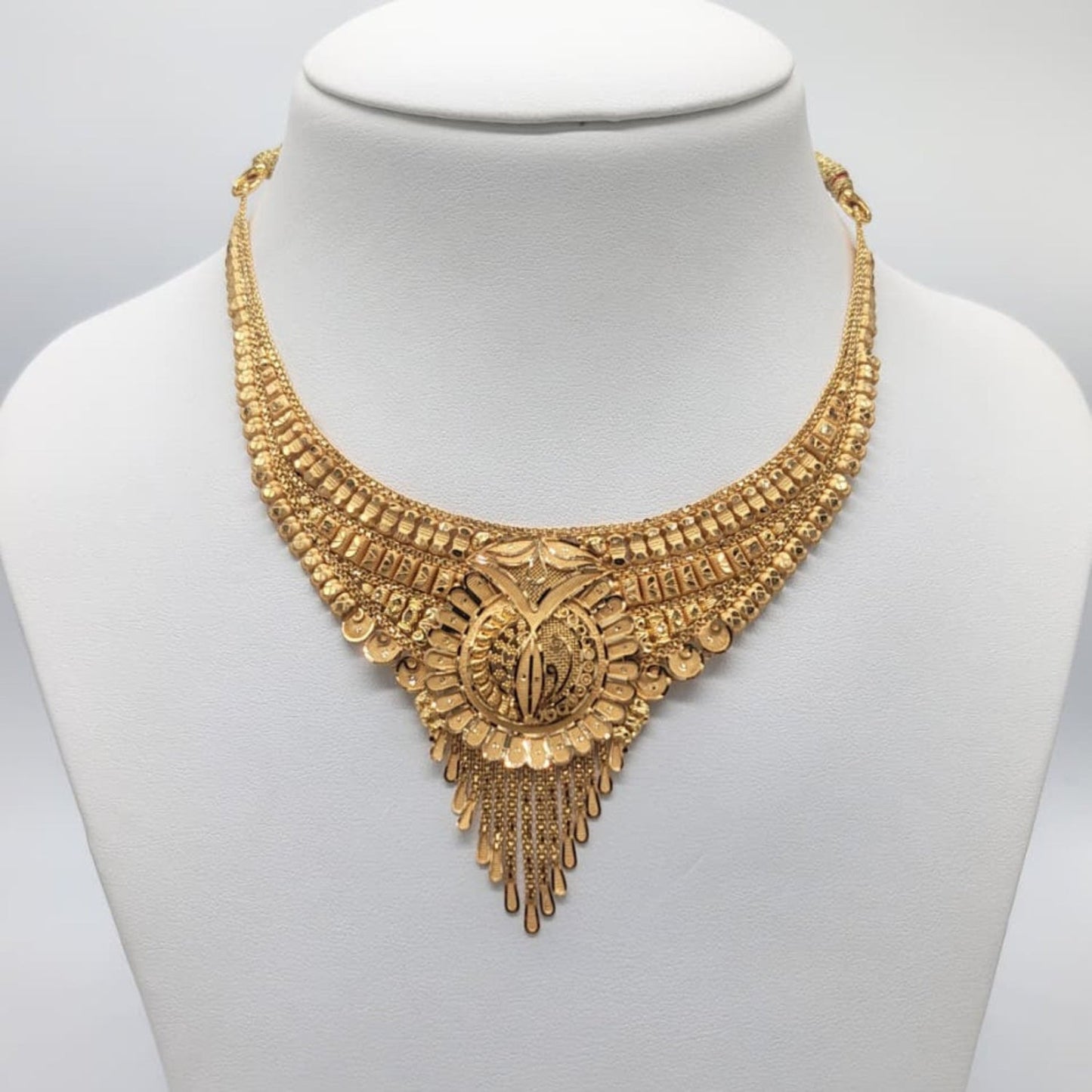 Gold necklace on a mannequin with weight and material information displayed.