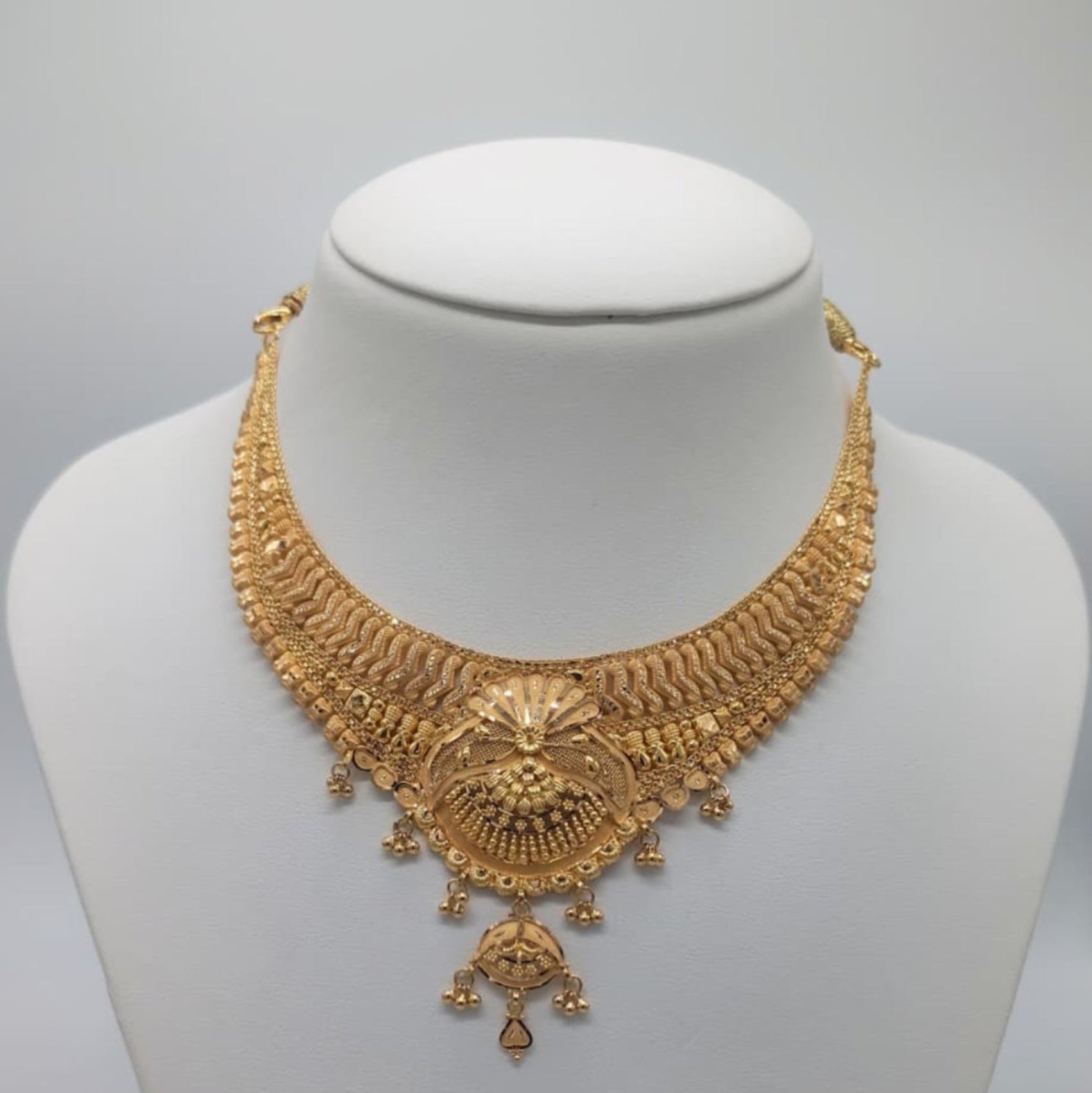 Gold necklace on a mannequin bust with weight displayed