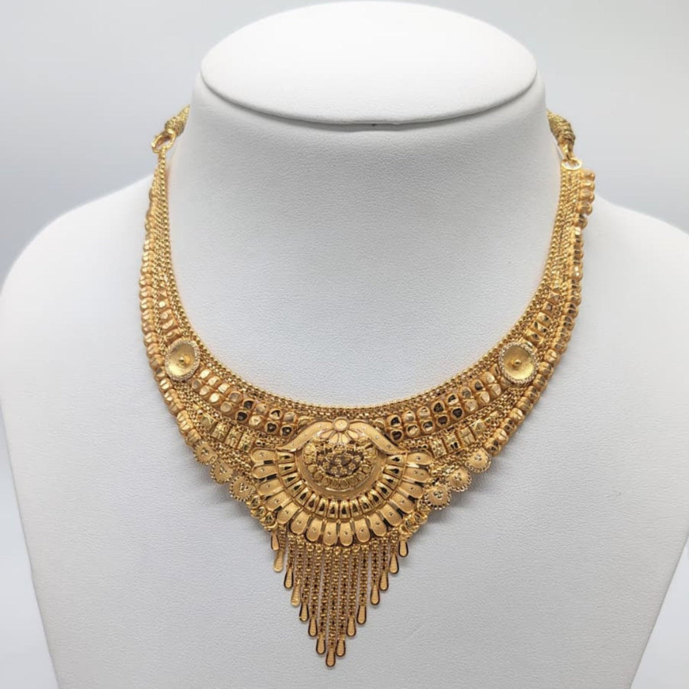 Gold necklace on a mannequin with a plain background