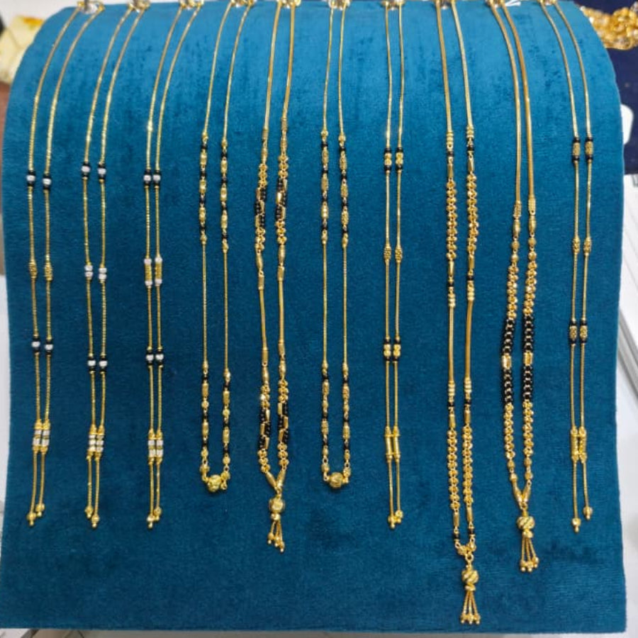 A display of multiple gold-toned beaded necklaces and chains arranged on a teal velvet jewelry stand, photographed on a white tabletop with a person partially visible in the background.