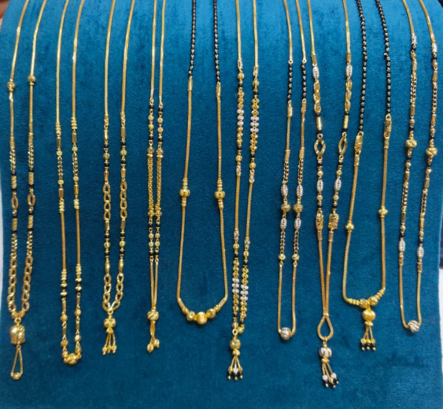 A hand holds up a teal velvet jewelry display bust filled with multiple gold-tone and black beaded necklaces, shown against a retail counter with papers and a phone in the background.