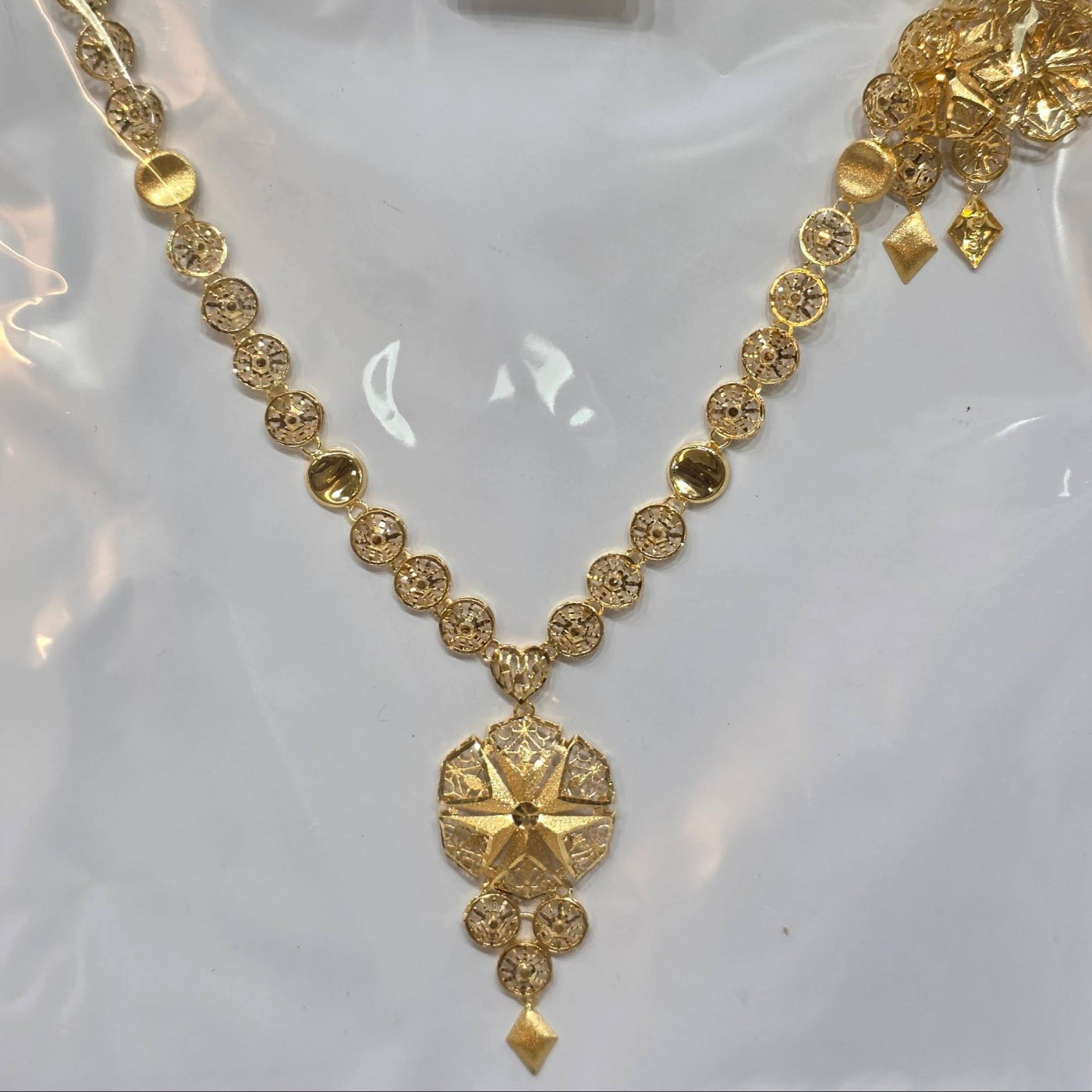 Gold necklace with intricate design on a white background