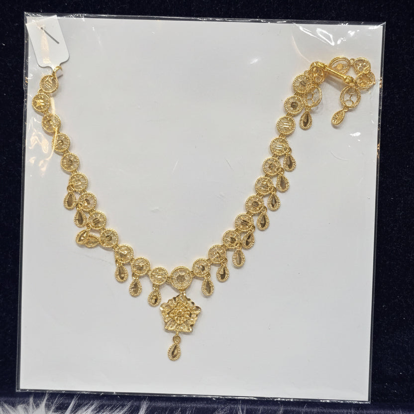 Gold necklace on a clear plastic sheet with a black background