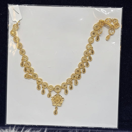Gold necklace on a clear plastic sheet with a black background