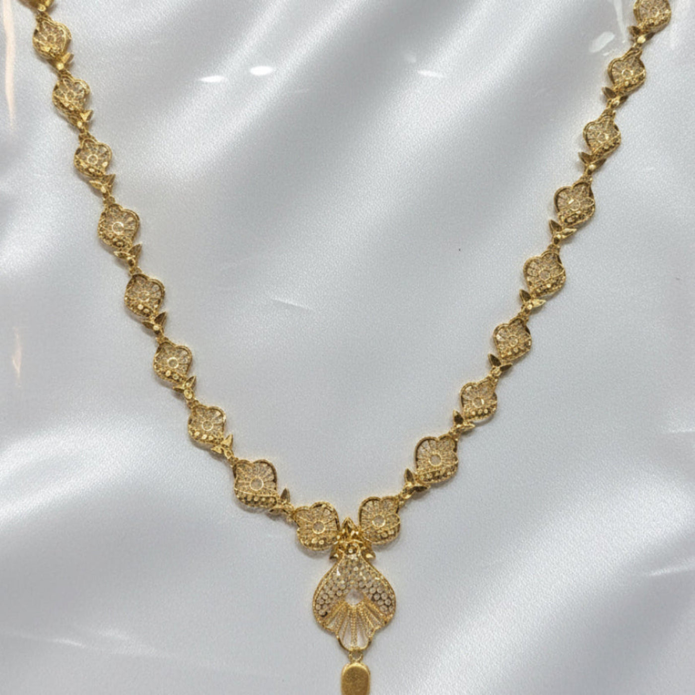 Gold necklace on a white card with a visible price tag.