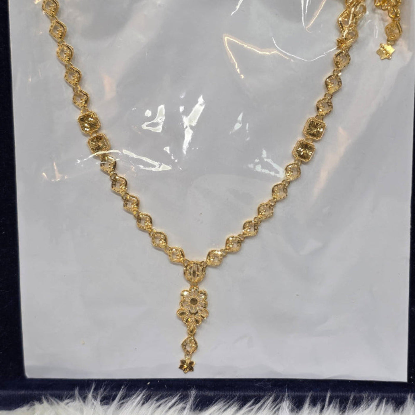 Gold necklace on a white card with a clear plastic cover
