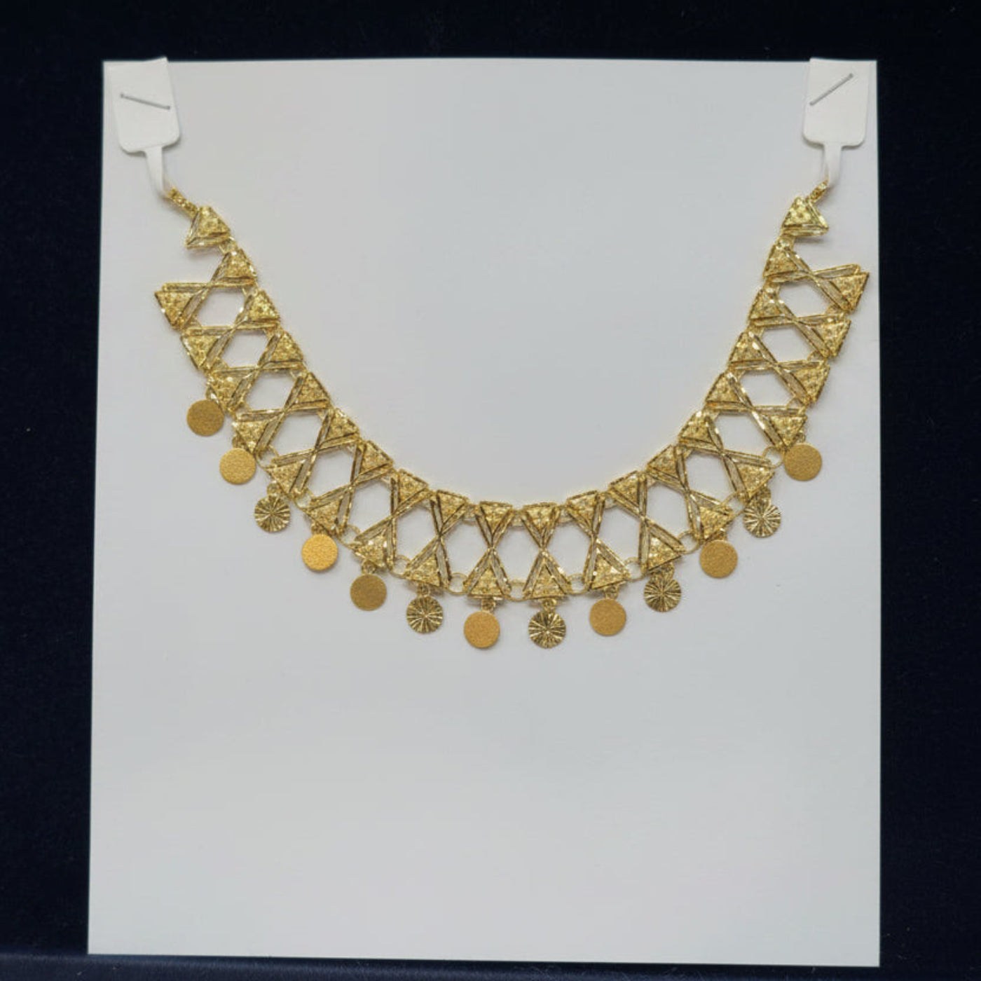 Gold necklace on a white card with a black background