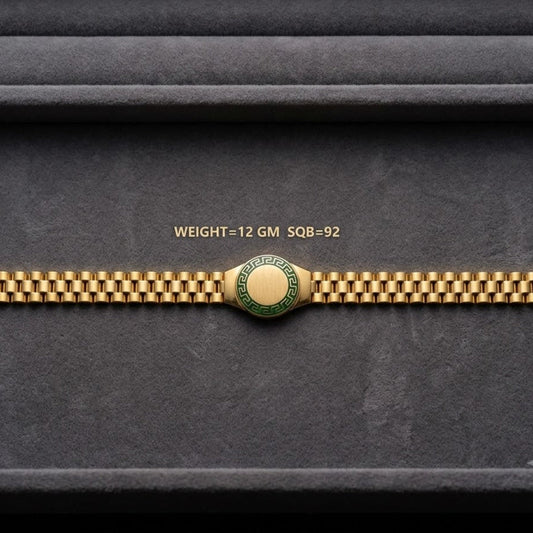 A gold-tone watch band with a central round green and gold emblem, displayed horizontally on a dark gray textured background. Small gold text above the band reads 'WEIGHT=12 GM SQ8-92'.