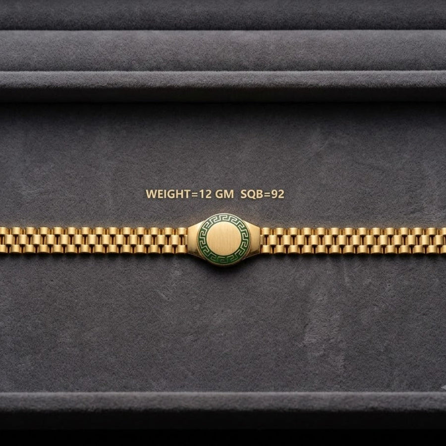 A gold-tone watch band with a central round green and gold emblem, displayed horizontally on a dark gray textured background. Small gold text above the band reads 'WEIGHT=12 GM SQ8-92'.